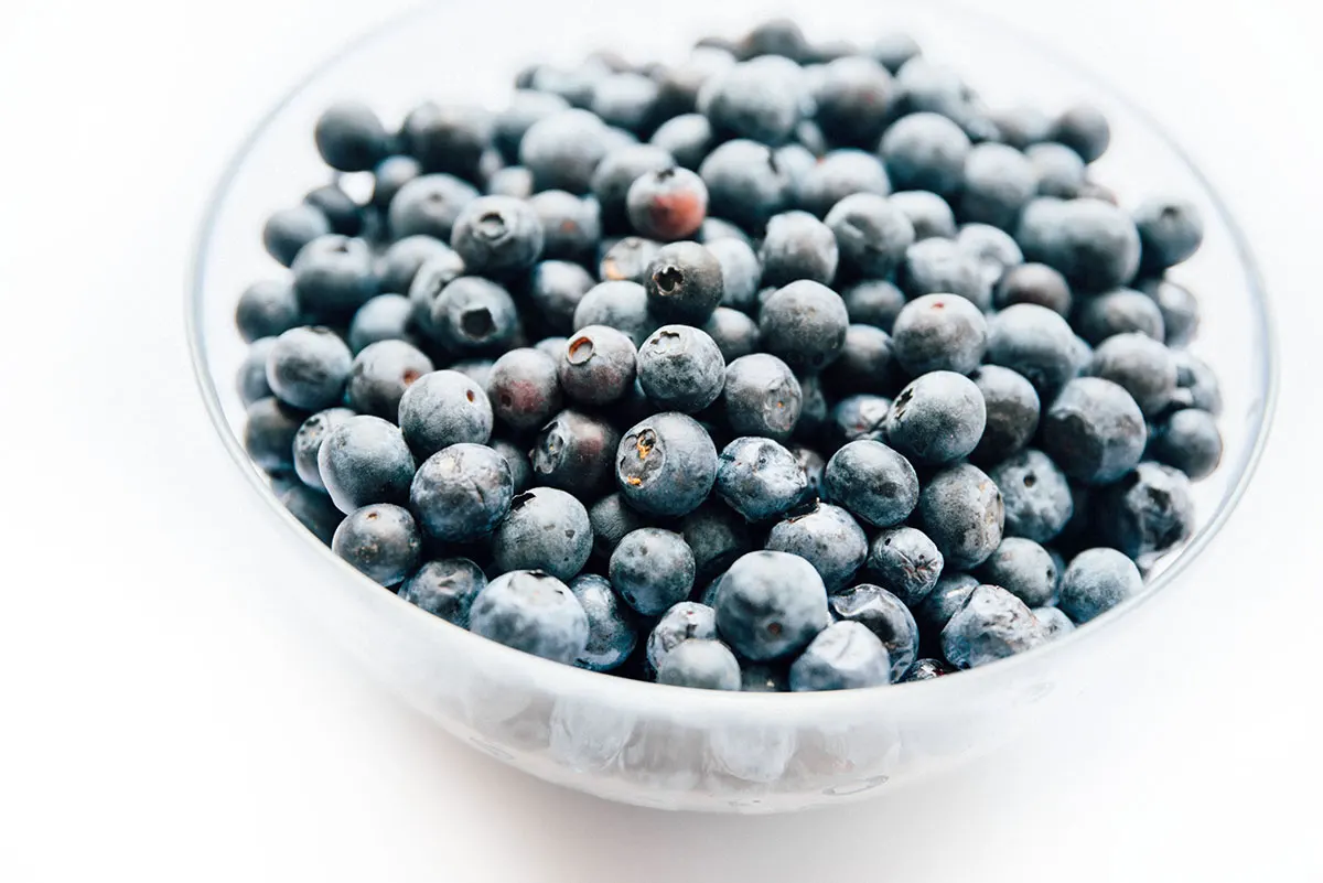 A clear glass bowl filled with blueberries