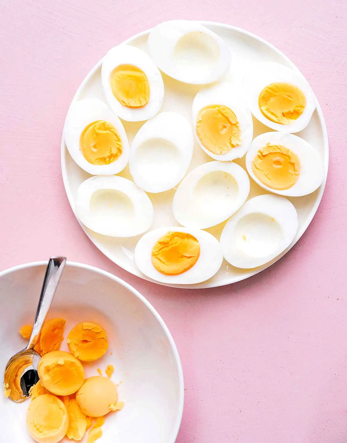 A plate of hardboiled eggs on a pink background