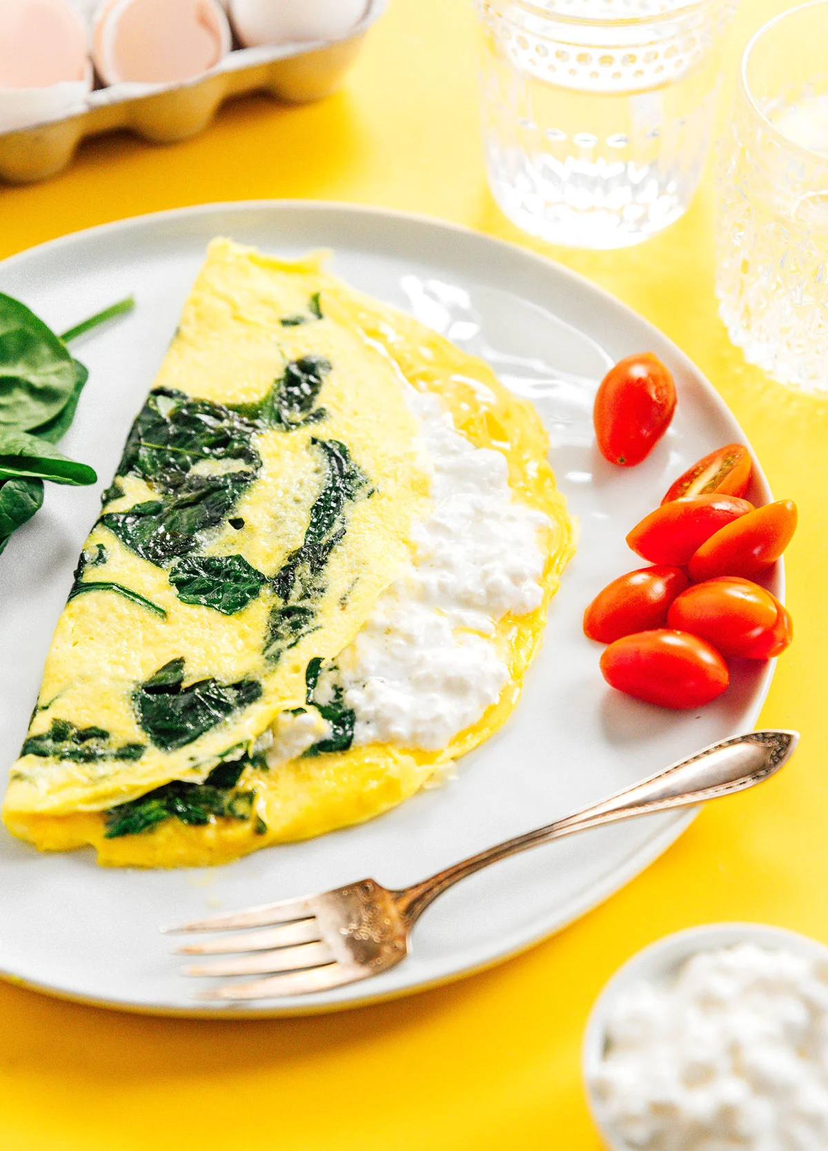 A cottage cheese omelette with spinach on a plate with cherry tomatoes