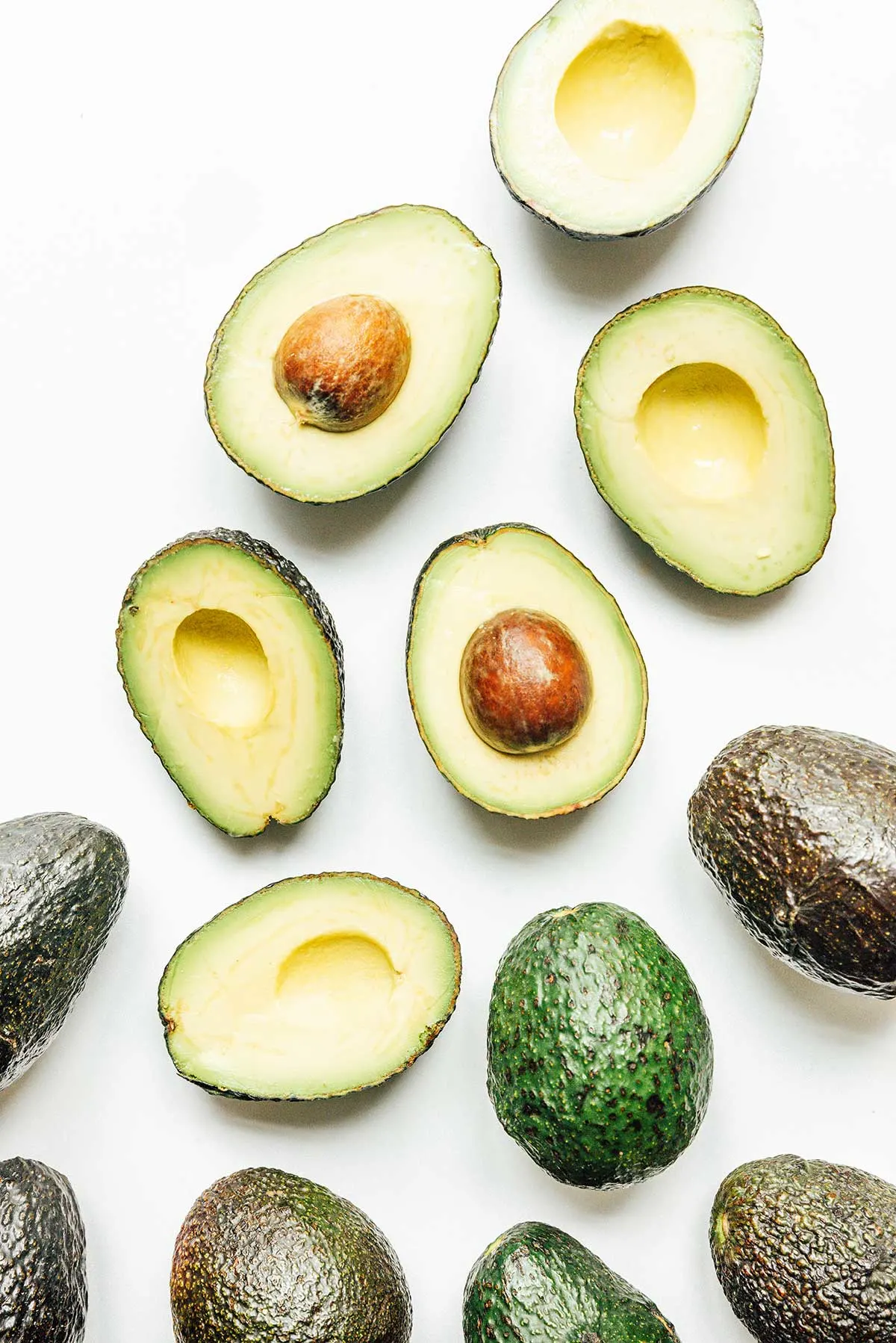 Halved avocados on a white background from above