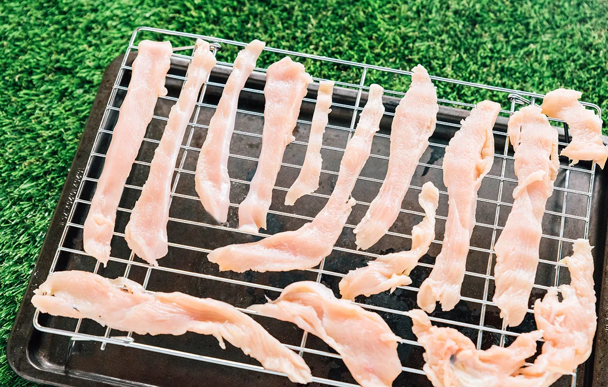 chicken strips on a baking rack before being cooked.
