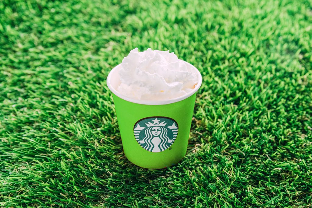 A plain pup cup of whipped cream in a green mini starbucks cup.