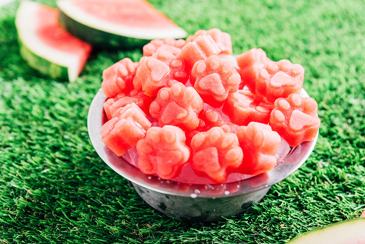 A bowl of frozen watermelon treats on ice with watermelon slices in the background.