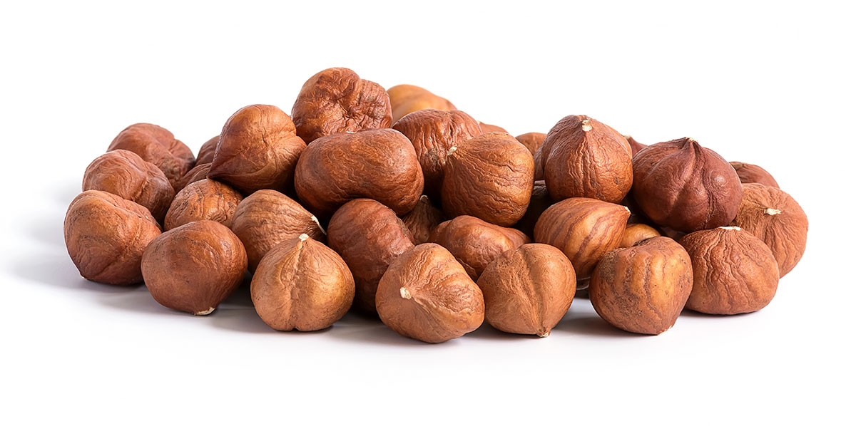 Pile of hazelnuts on white background.