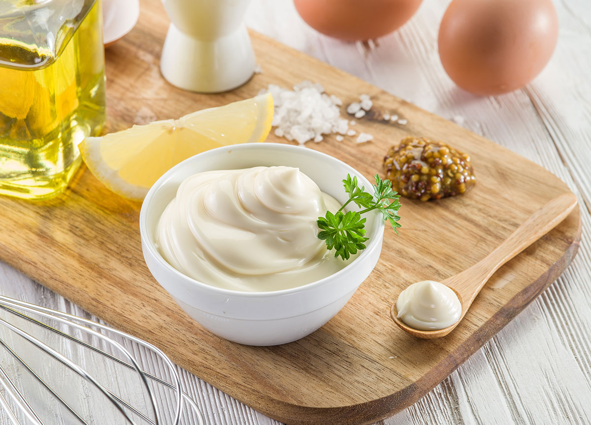 Ingredients to make mayonnaise on a wooden board.