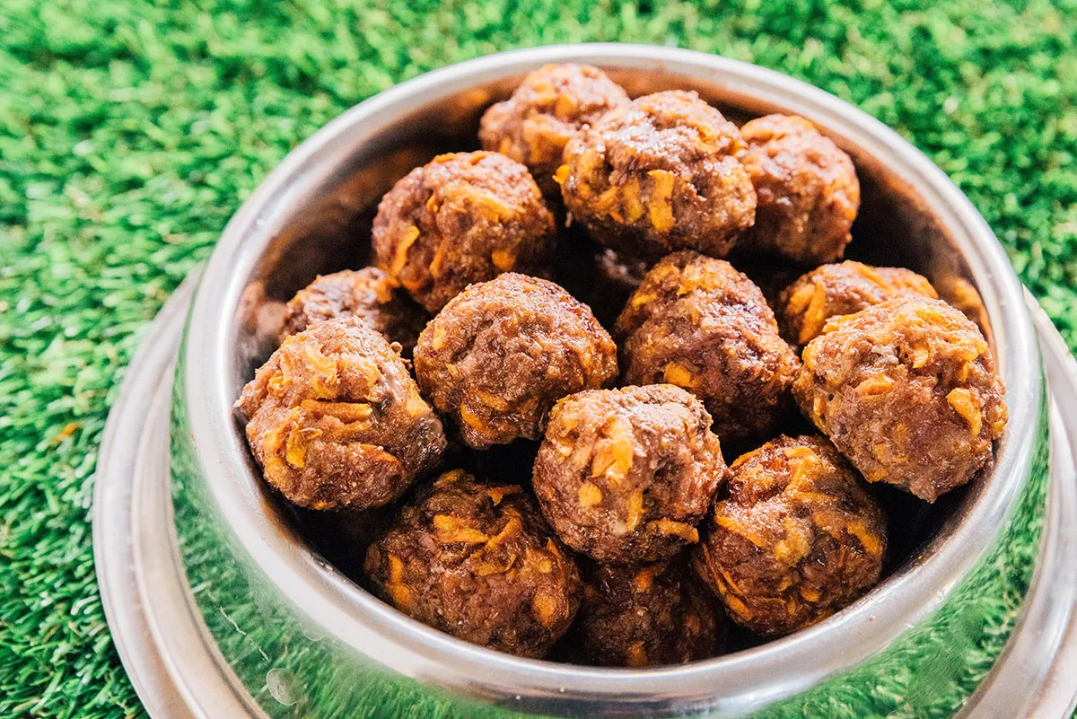 Dog meatballs stacked high in a metal dog bowl.