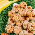 Paw-shaped bacon dog treats on grass.