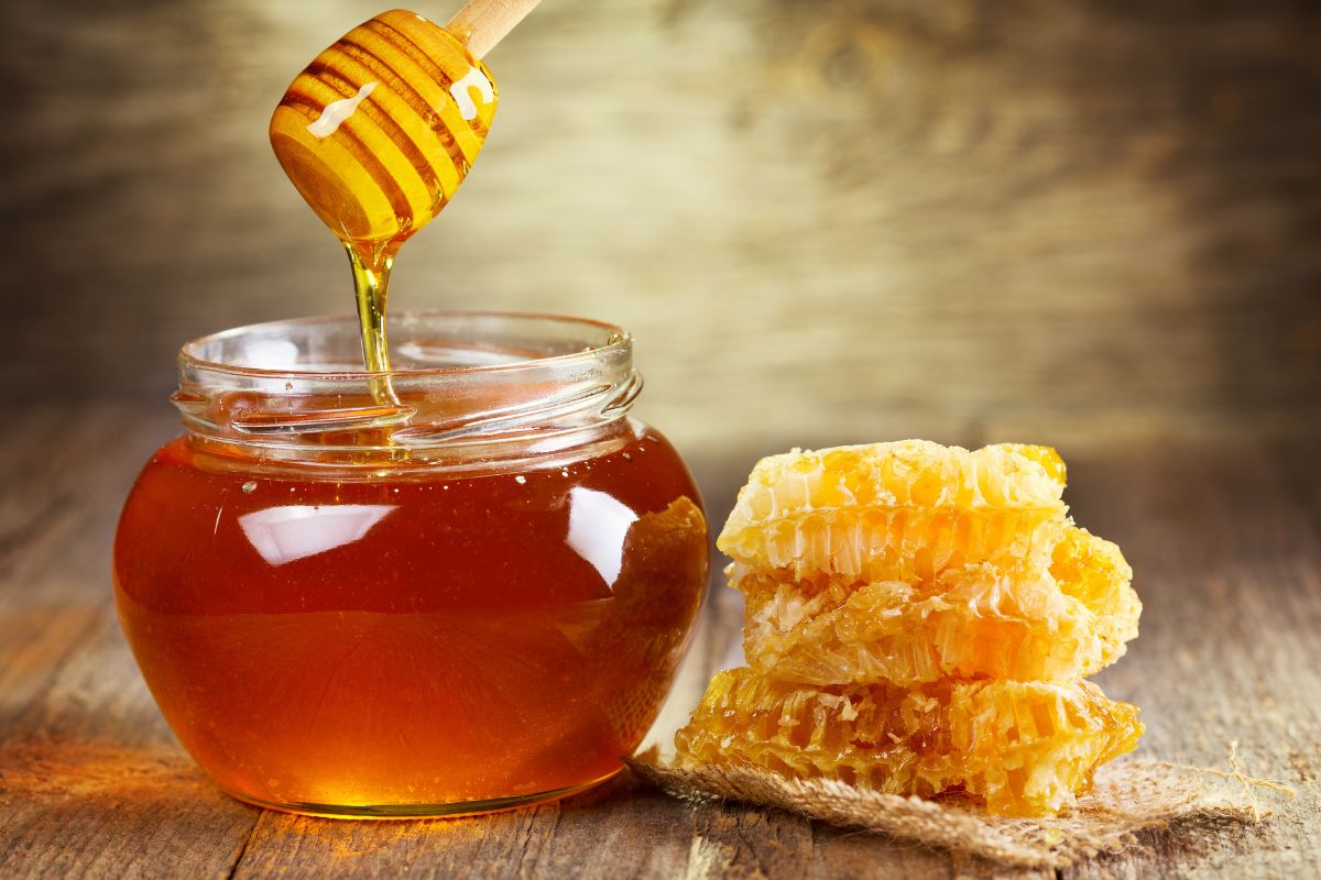 A jar of honey next to honey comb.