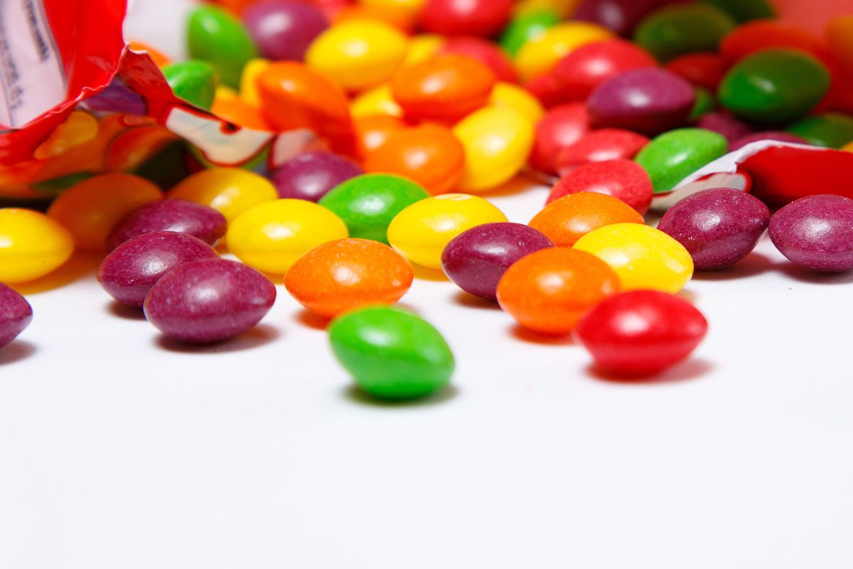 Skittles coming out of a bag on a white background.